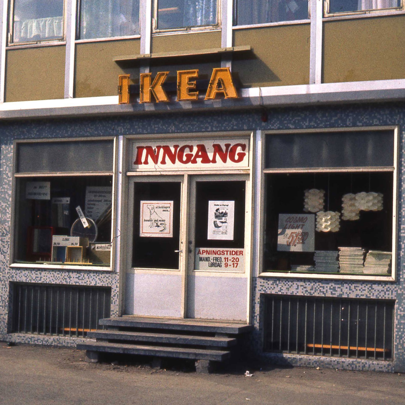 Entrance IKEA store in Norway, 1960s. Yellow IKEA sign above door. Lamps and catalogue stacks visible in shop windows.