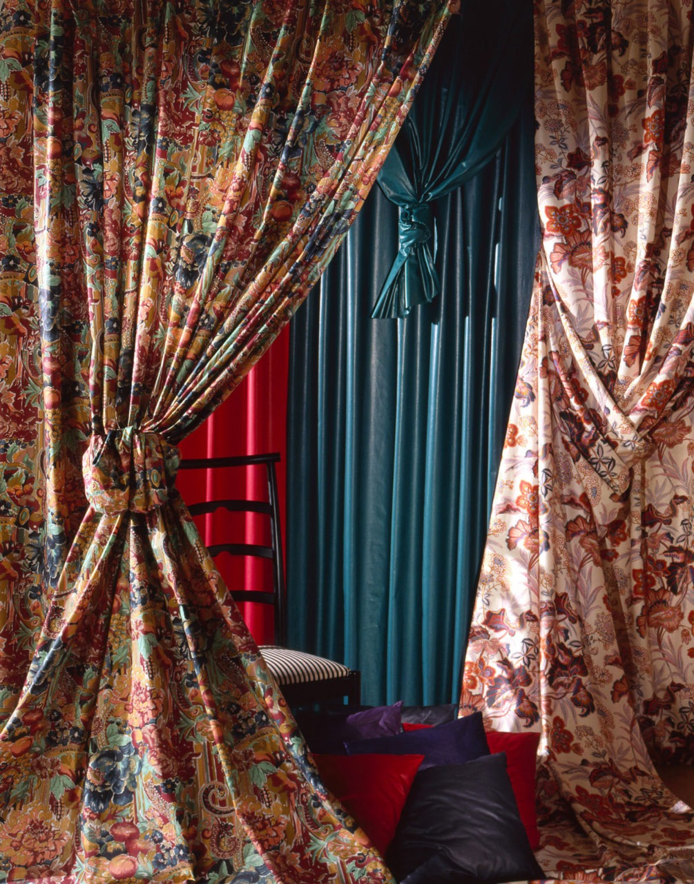 Room with curtains and roller blind in multicolored floral pattern, leather armchair.