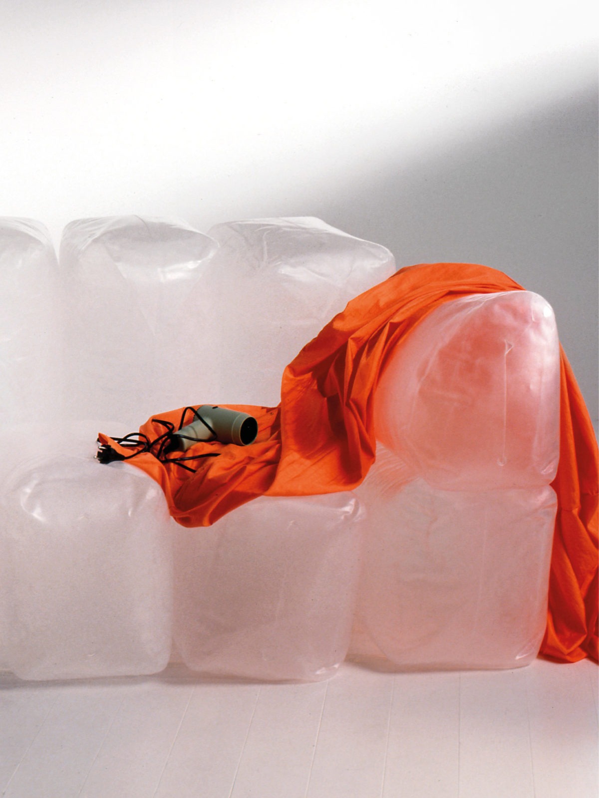 A hair-dryer sits on top of the inflatable sofa INNERLIG. An orange textile cover is draped over one armrest.