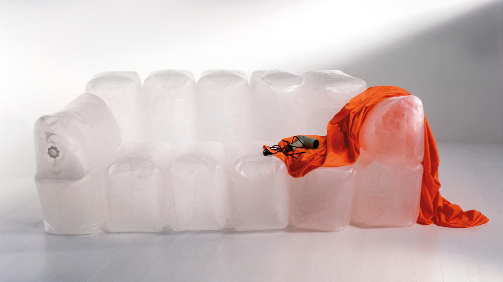 A hair-dryer sits on top of the inflatable sofa INNERLIG. An orange textile cover is draped over one armrest.