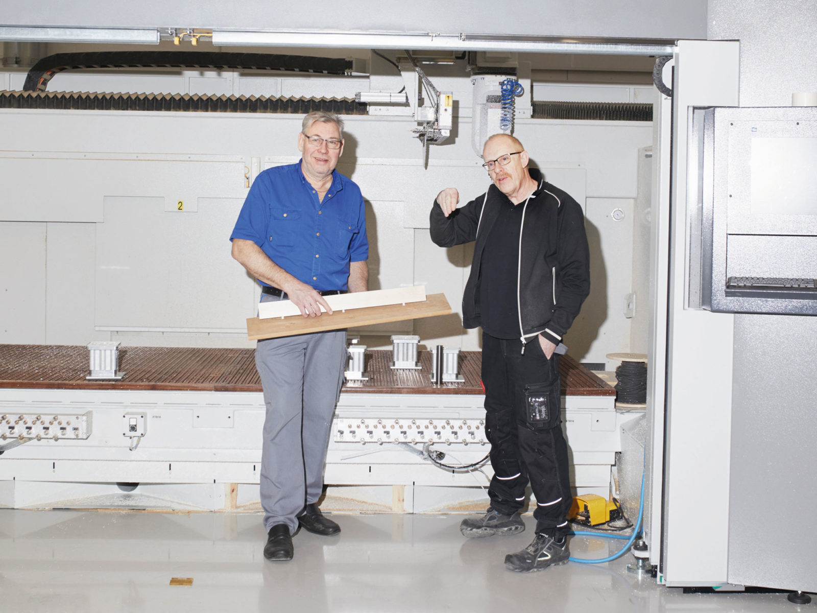 Two middle-aged men, Anders Eriksson and Göran Sjöstedt, standing in a brightly lit clean workshop area.