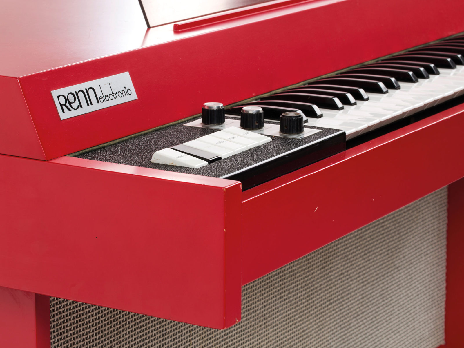 Primer plano de un piano rojo; en él se lee: «RENN electronic».