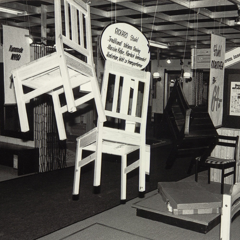 Photo from a 1970s IKEA store shows a messy display of chairs, signs and a flatpack.