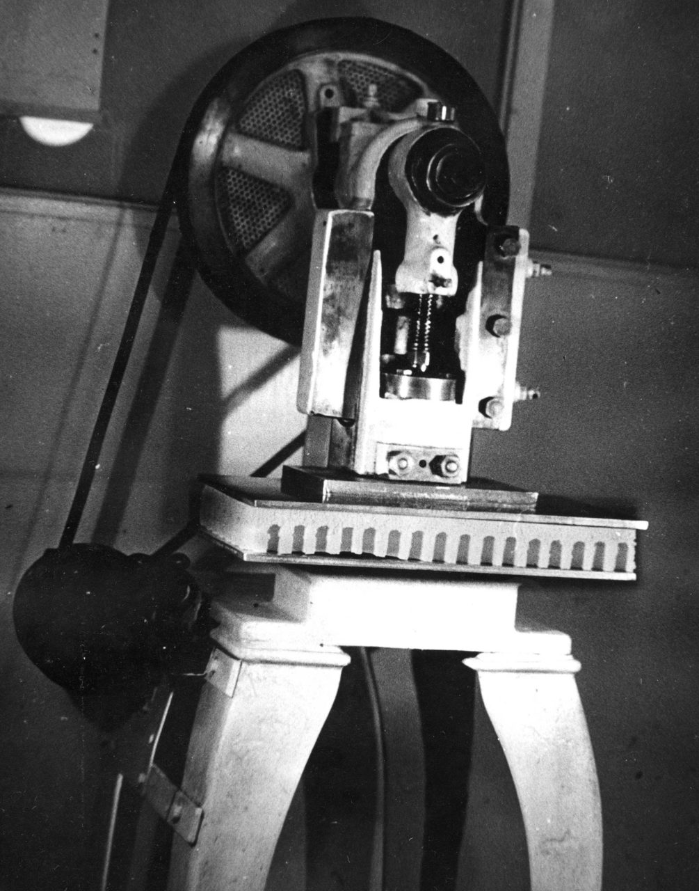 Schwarz-Weiß-Foto einer großen Maschine, die wie eine Standbohrmaschine aussieht.