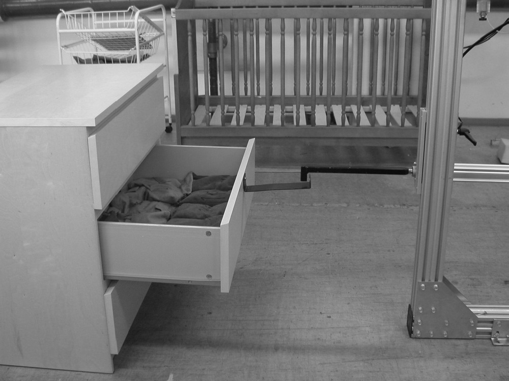 Black and white photo of test machine pulling out and closing the drawer in a white dresser.