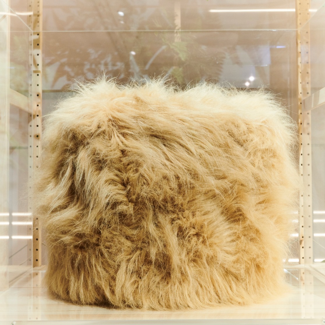 A beige fake fur cover looking like a pouffe, used to cover up a WiFi router.