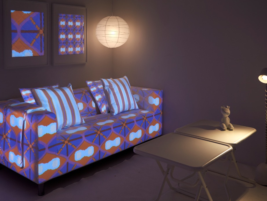 Ett rum med en soffa, kuddar och väggramar med ett grafiskt mönster i blått och brunt som skapats med en digital mönstermaskin.