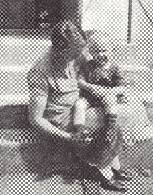 Woman sits on steps with toddler on knee, Berta Kamprad with son Ingvar, in 1930s clothes.