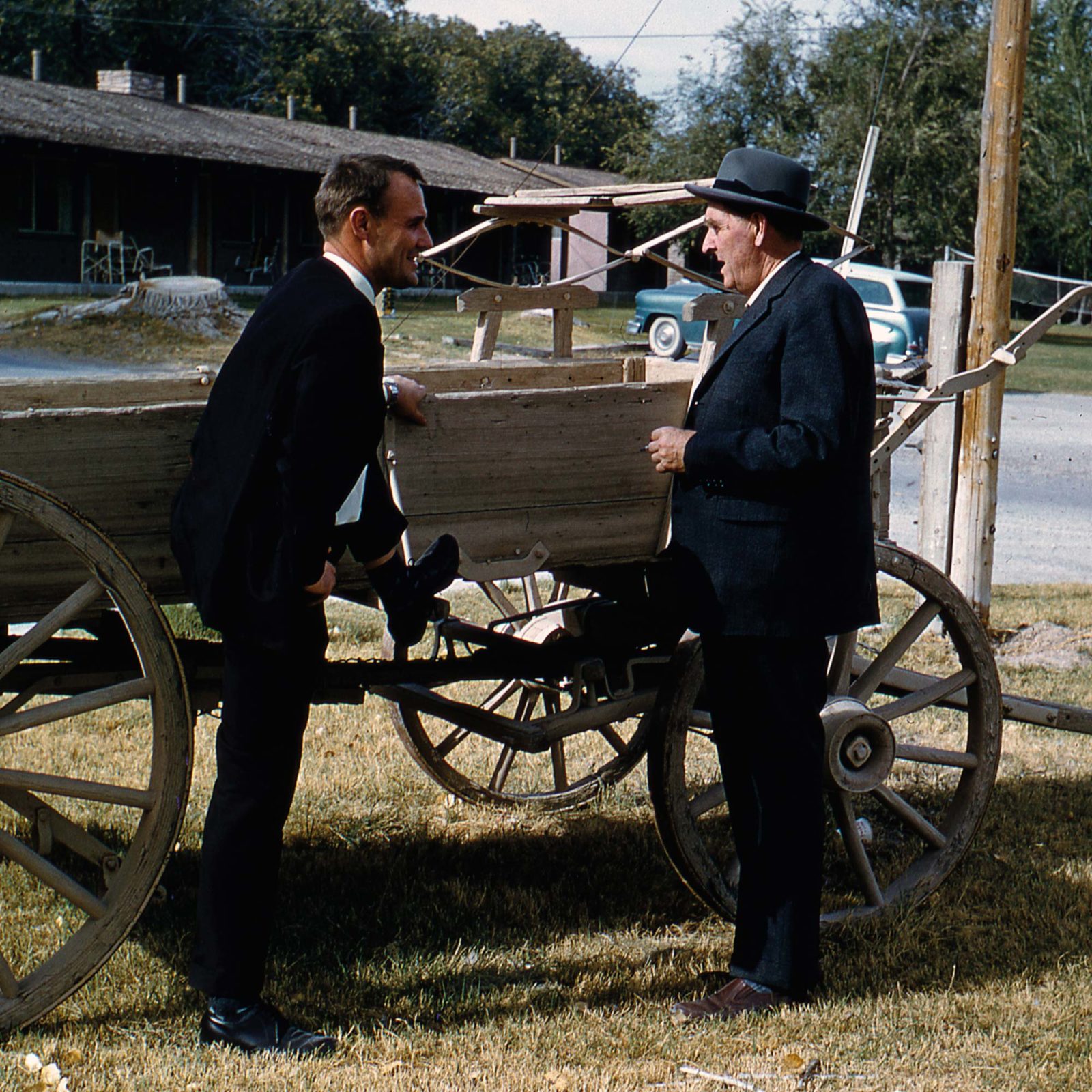 Ingvar Kamprad speaking with his father Feodor next to an old wooden wagon.