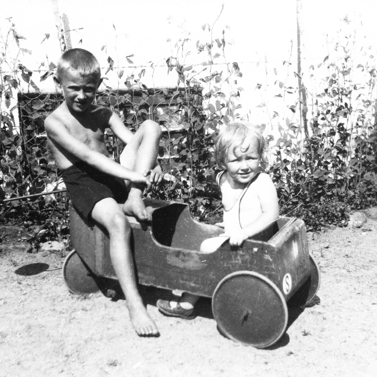 Dos niños pequeños (Ingvar Kamprad y su hermana Kerstin) juegan con un cochecito de madera un día de verano.