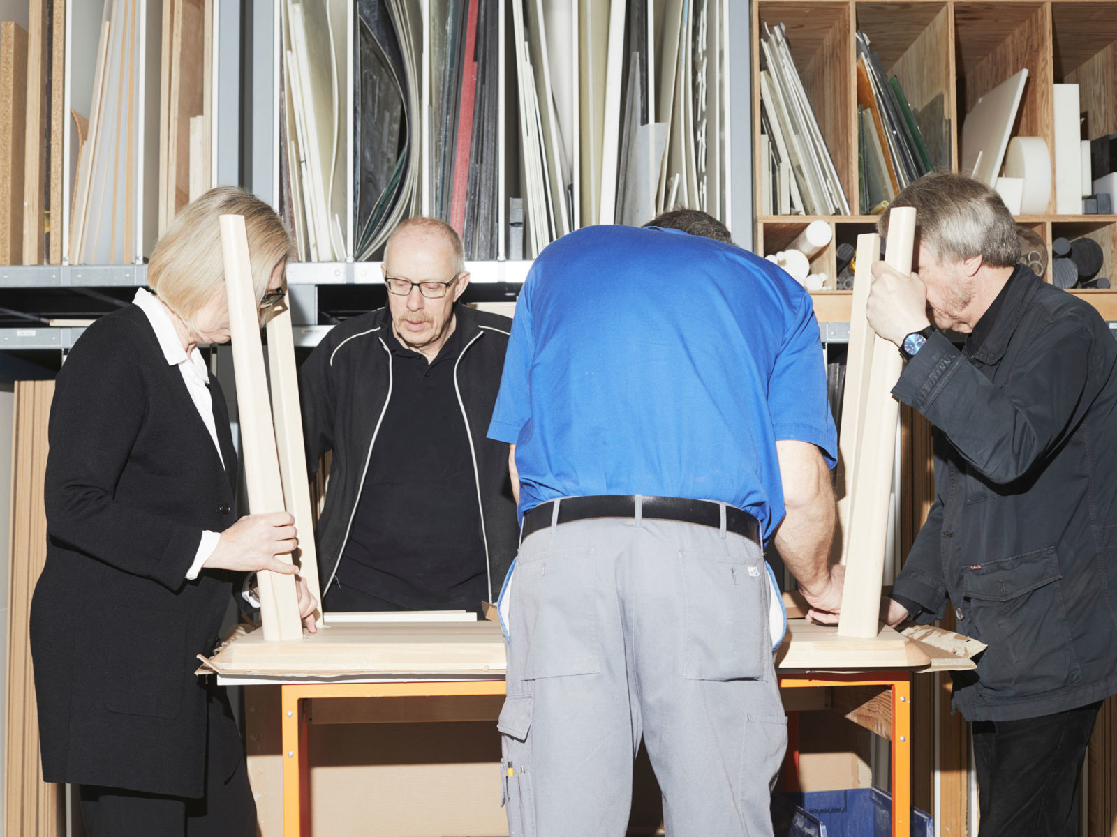 Four middle-aged persons, one woman, three men, working together on a table turned upside down.