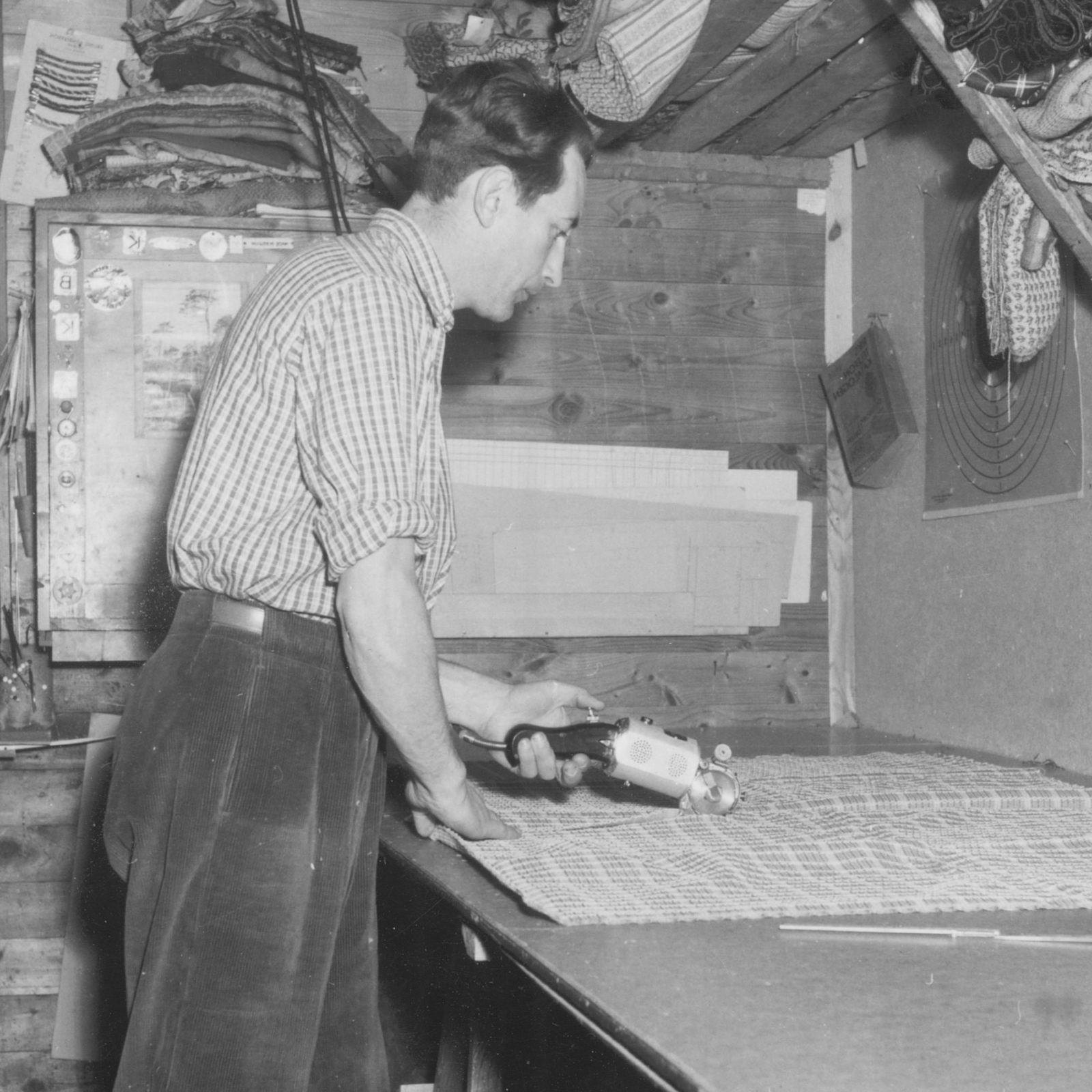 Homme coupant du tissu avec un cutter rotatif, années 1940.