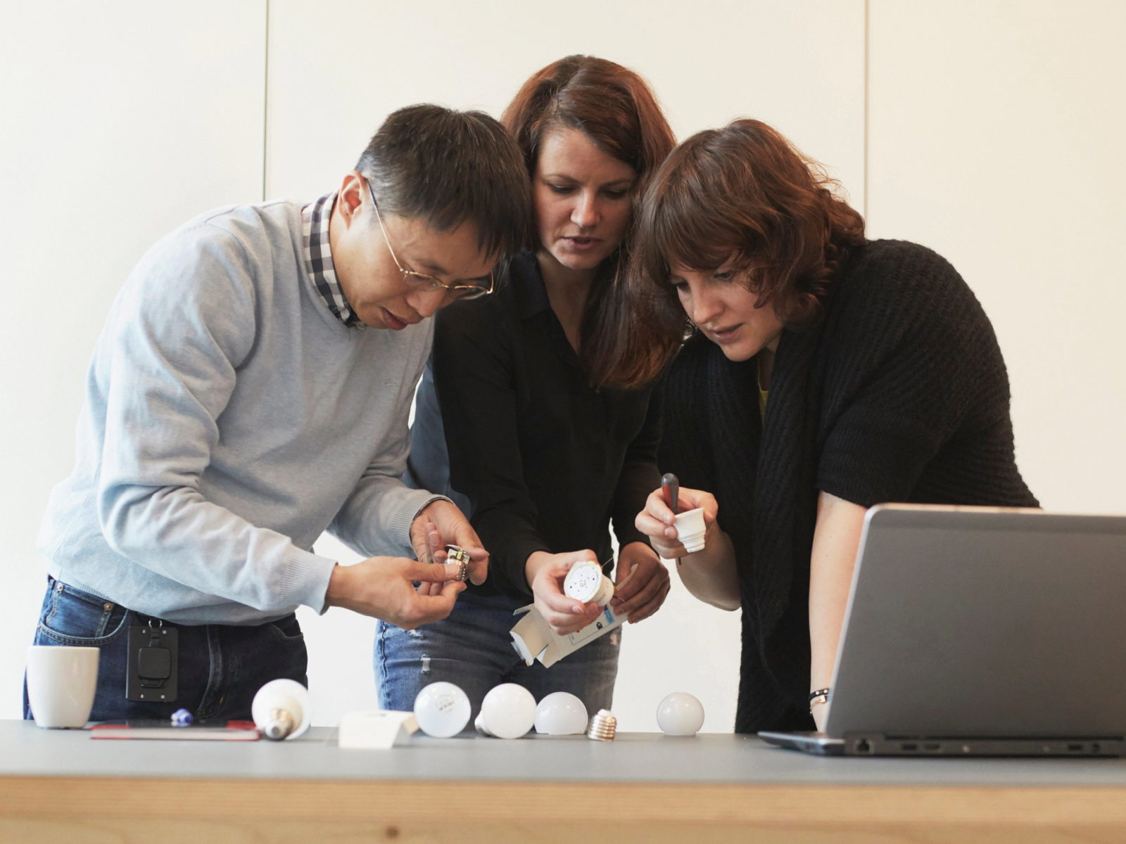 Produktutvecklare Victor Zeng, Magdalena Pinczakowska och Paulina Pajak står tätt ihop och undersöker delar av LED-lampor.