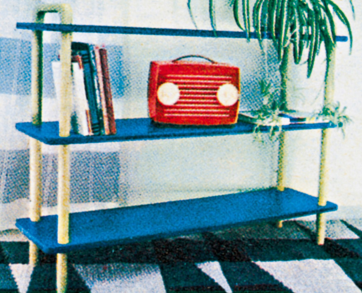 A red radio stands on a shelf in a blue-lacquered bookcase.