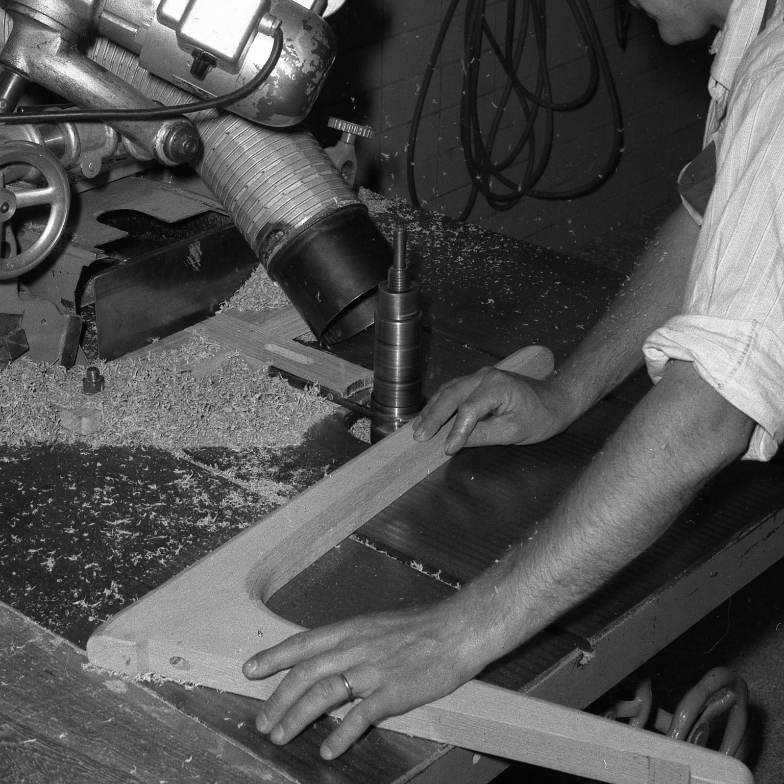 Gros plan, homme travaillant une pièce de meuble en bois sur une ponceuse, années 1940.