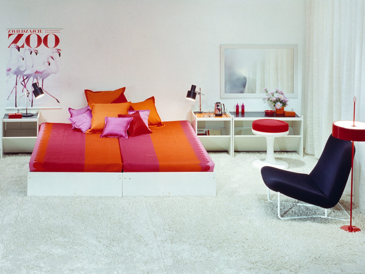 Weißes Schlafzimmer mit bunten Details, HEPP Bett, rosa- und orangefarbene Textilien, die an Bonbonpapier erinnern.
