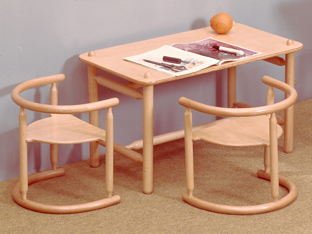 Tisch und zwei Stühle in Kindergröße, komplett aus hellem Holz. Korpus und Details mit weichen, runden Formen.