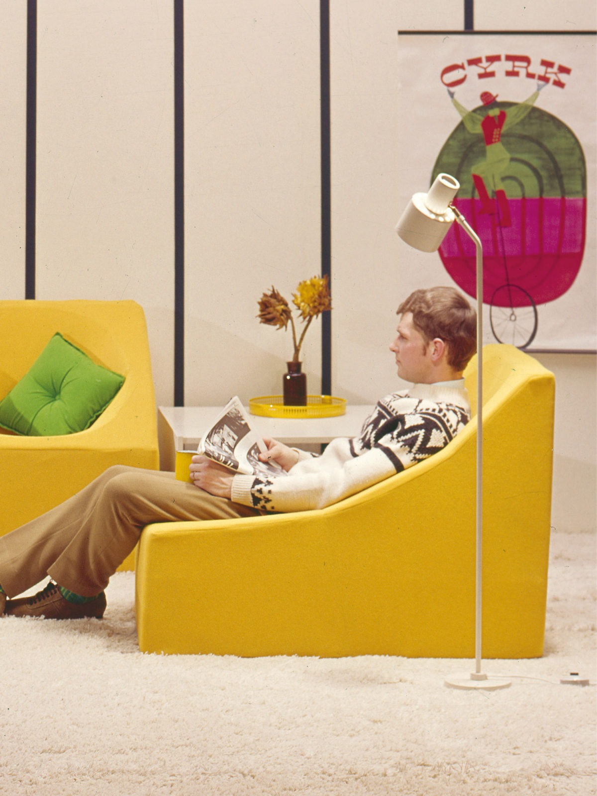 Low, yellow TROFÉ armchairs, like eggcups with straight sides, are placed as a corner sofa on a thick rug.