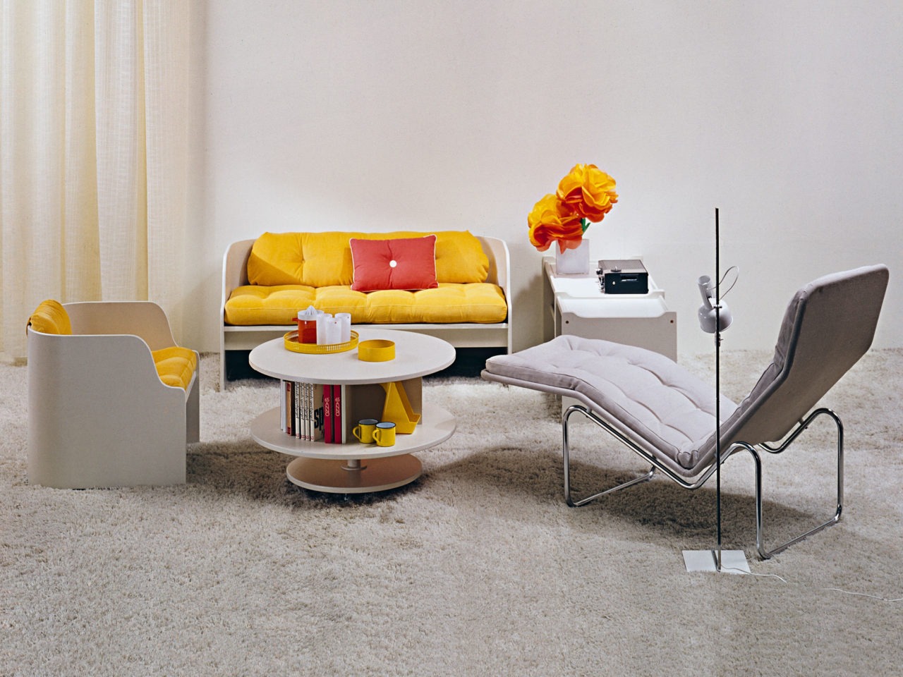 Pièce claire, détails jaunes et rouges. Salon KATINKA en panneaux courbes fins, placés autour d’une table tournante KARUSELL.