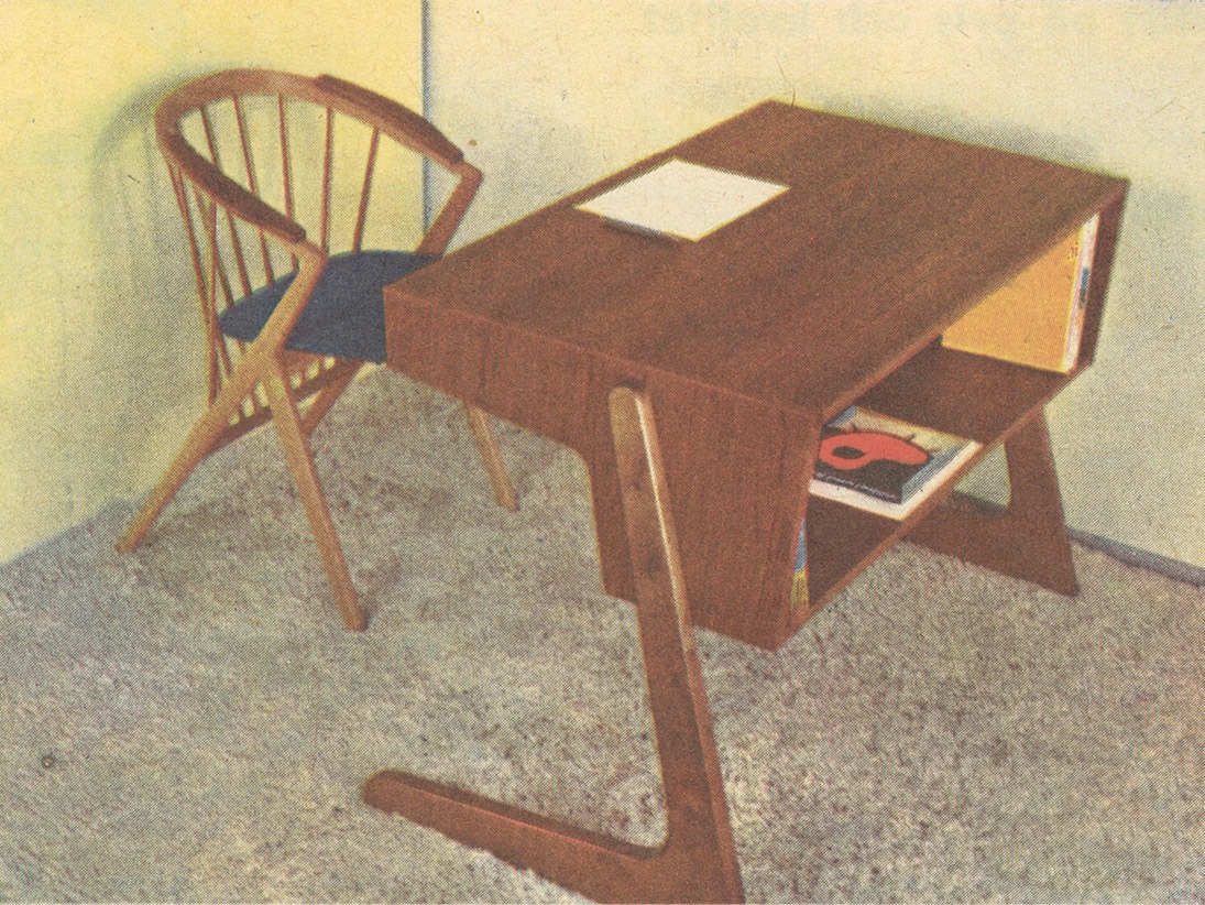 Sillón con respaldo de listones de madera, reposabrazos y escritorio SCRIBO, con patas en L y estantería sobre alfombra.