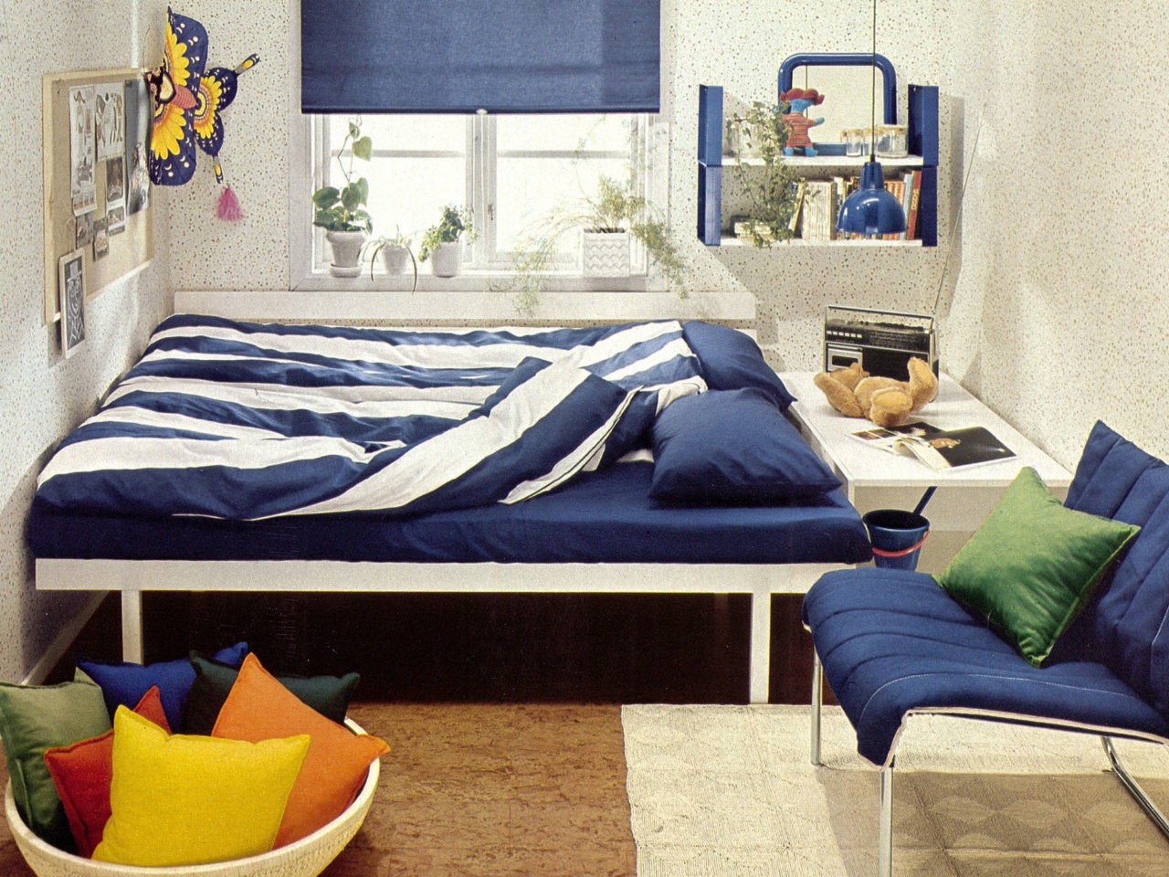 Habitación con estampado de lunares, suelo de corcho, ropa de cama a rayas azules y blancas, y detalles en azul.