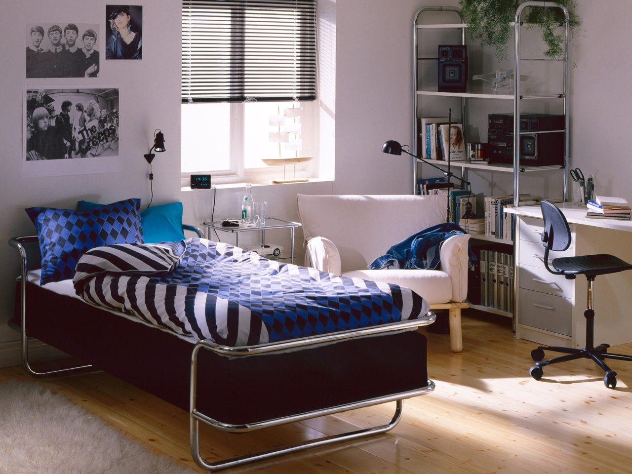 Ett tonårsrum i mestadels vitt med ljust trägolv. En säng, modell KROMVIK, och en bokhylla har förkromade metallrörsstommar.