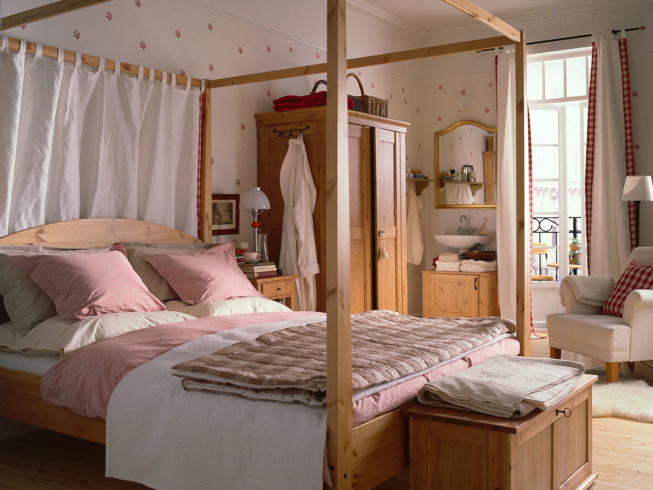 Ett sovrum med en dubbelsäng med stor, överbyggd sängram. Såväl säng som övriga möbler av modell MORGONDAL, i patinerat trä.