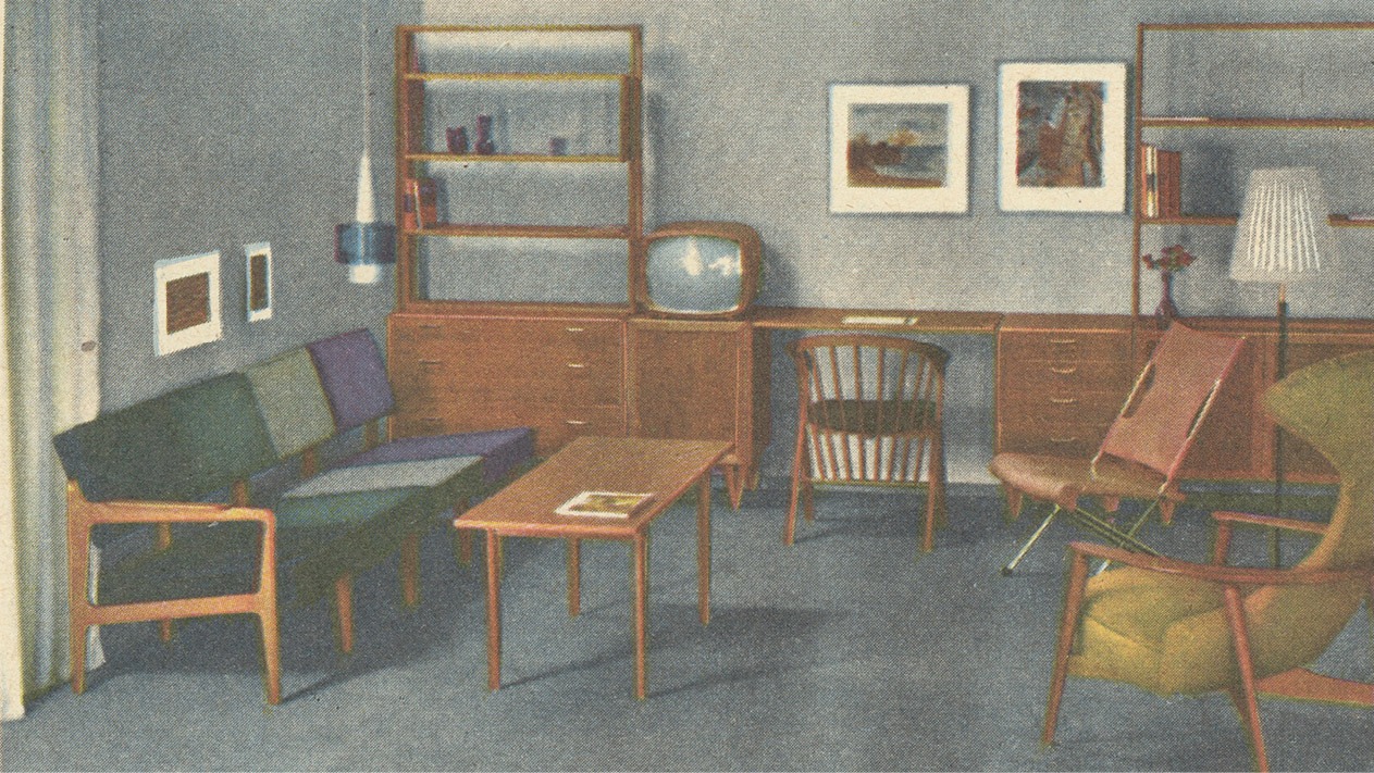 Vardagsrum med en spridd sittgrupp, en tv och en sammanhängande kombination av bokhyllor, hurtsar och skrivbord längs väggen.