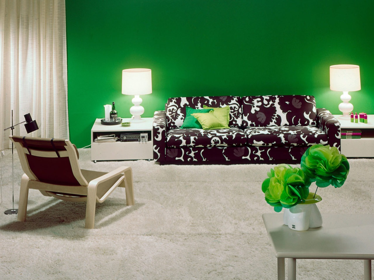 Svartvitmönstrad soffa, modell MIX, i ett rum med heltäckande matta och detaljer i vitt och dekorationer och vägg i illgrönt.
