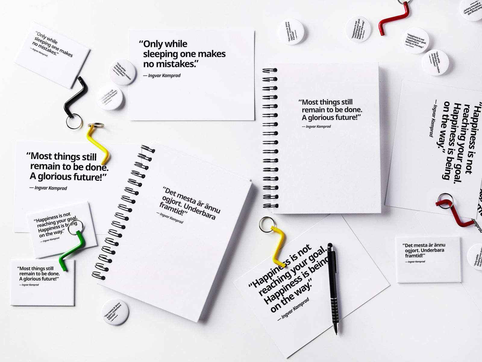 Nyckelringar med insexnycklar i olika färger, små pins med citat och vita anteckningsböcker med citat i svart.