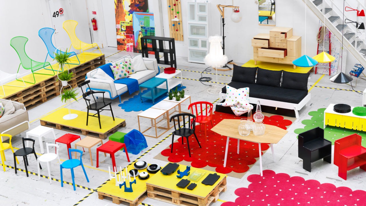 Stort rum med sittgrupper, bord, förvaringsmöbler och mattor i olika starka färger som grönt, rött, gult och blått.