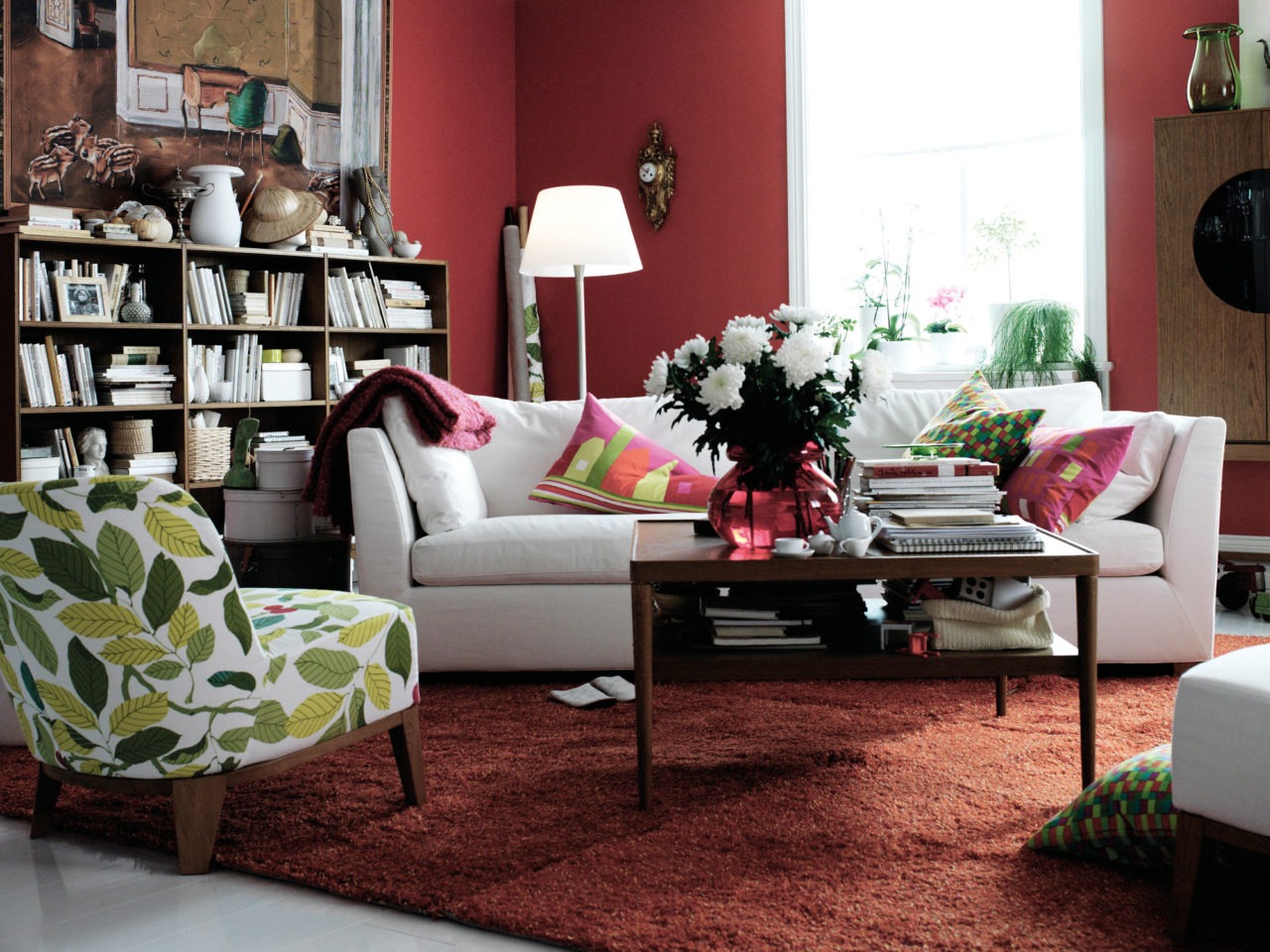 Living room with seating area, bookshelf, orange rug and burgundy walls.