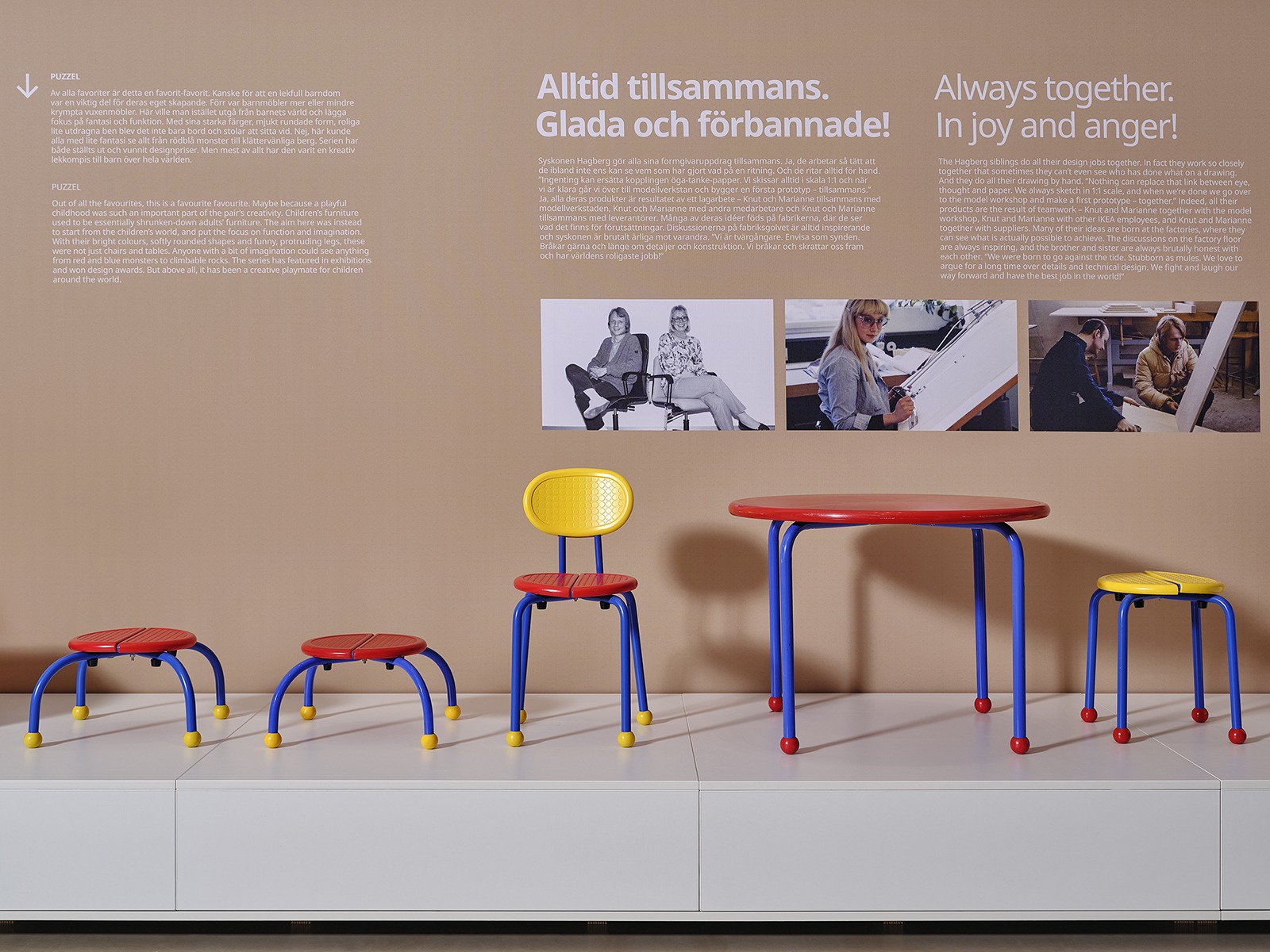 Colourful children's furniture exhibited on a low white podium against a beige wall with white information text and photographs.