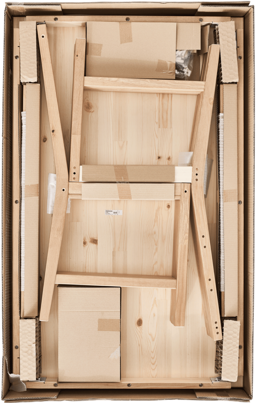 Opened IKEA flat pack seen from above containing the parts for a piece of blond wood furniture.