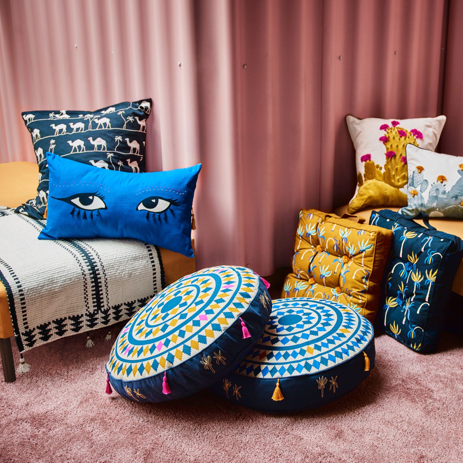 Brightly coloured handmade cushions, inspired by Jordanian handicrafts, including one pattern with big eyes and one with camels.