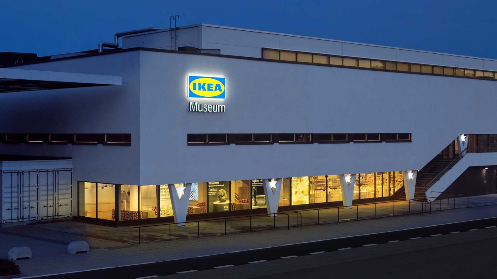 Stor vit byggnad sett i kvällsljus, en stort neonskylt på fasaden säger IKEA Museum.