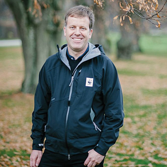 Middle-aged white man, Per Larsson, standing among autumn leaves in a blue jacket with WWF logo.