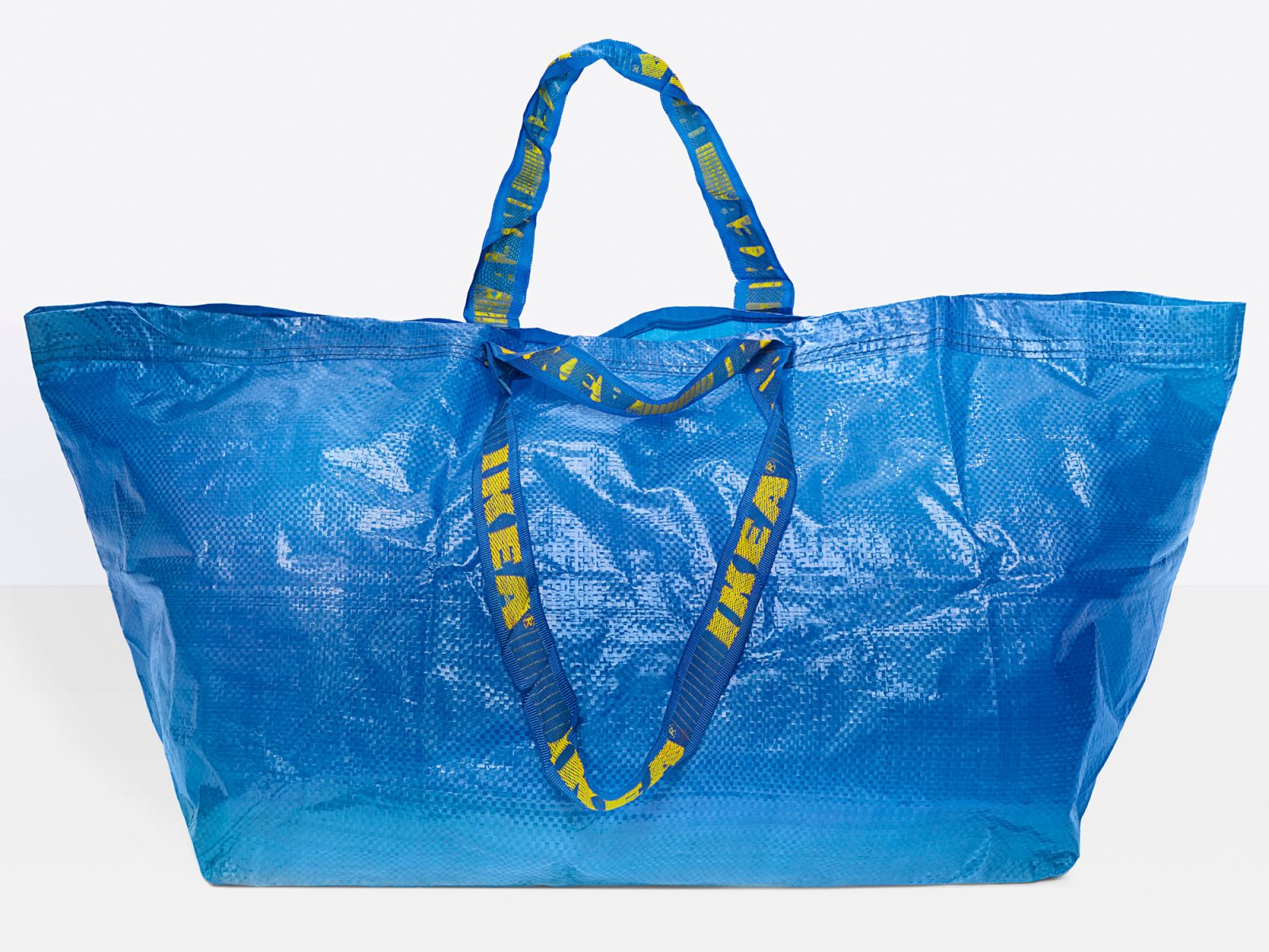 Un sac FRAKTA bleu, inscription IKEA jaune sur les poignées.