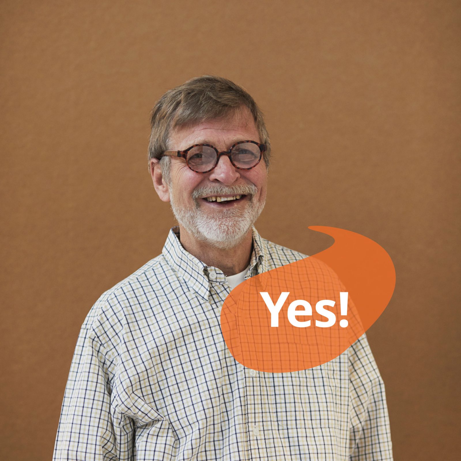 Grey-haired man in glasses and check shirt smiles. A speech bubble contains the text 'Yes'.
