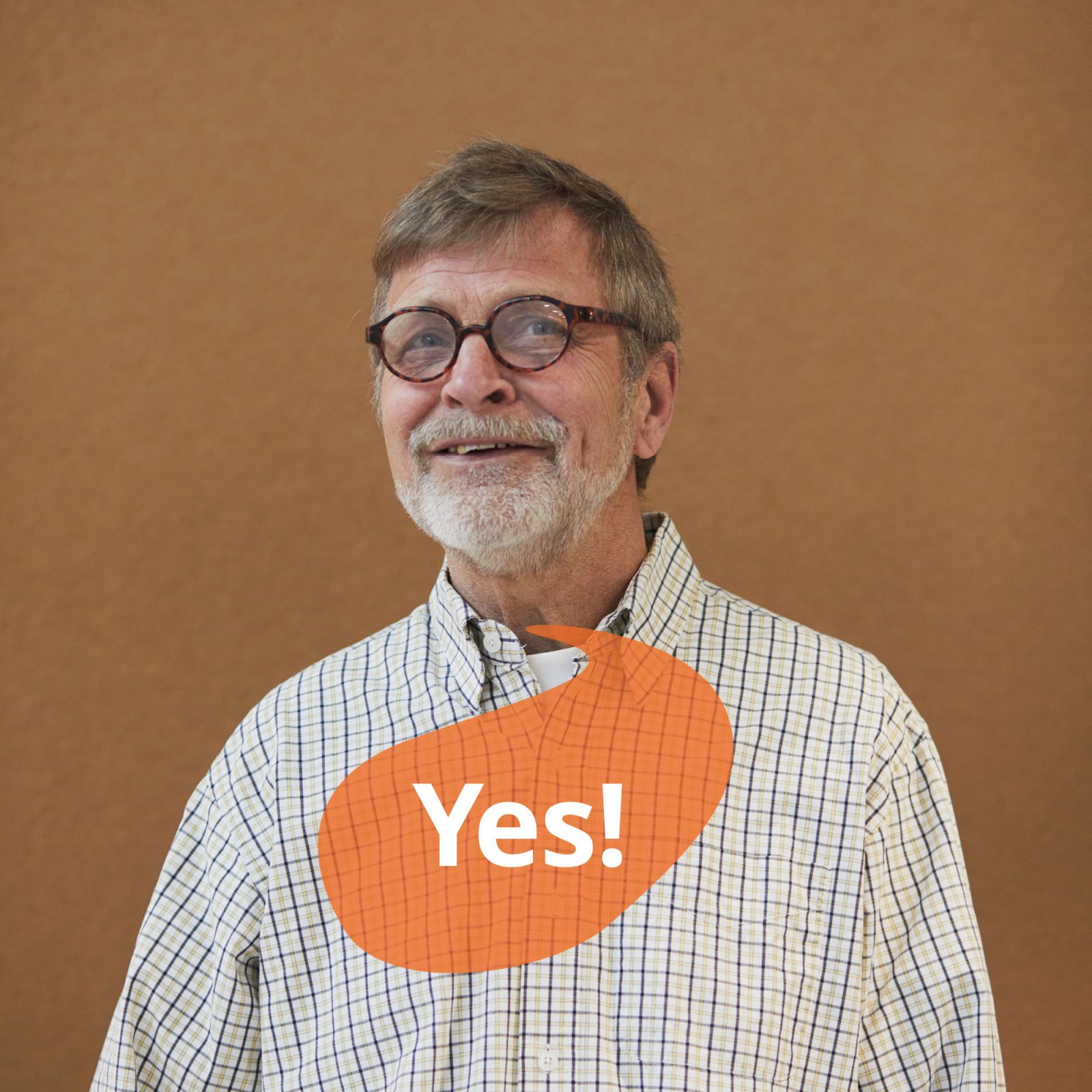 Grey-haired man in glasses and check shirt smiles and looks up. A speech bubble contains the text 'Yes'.