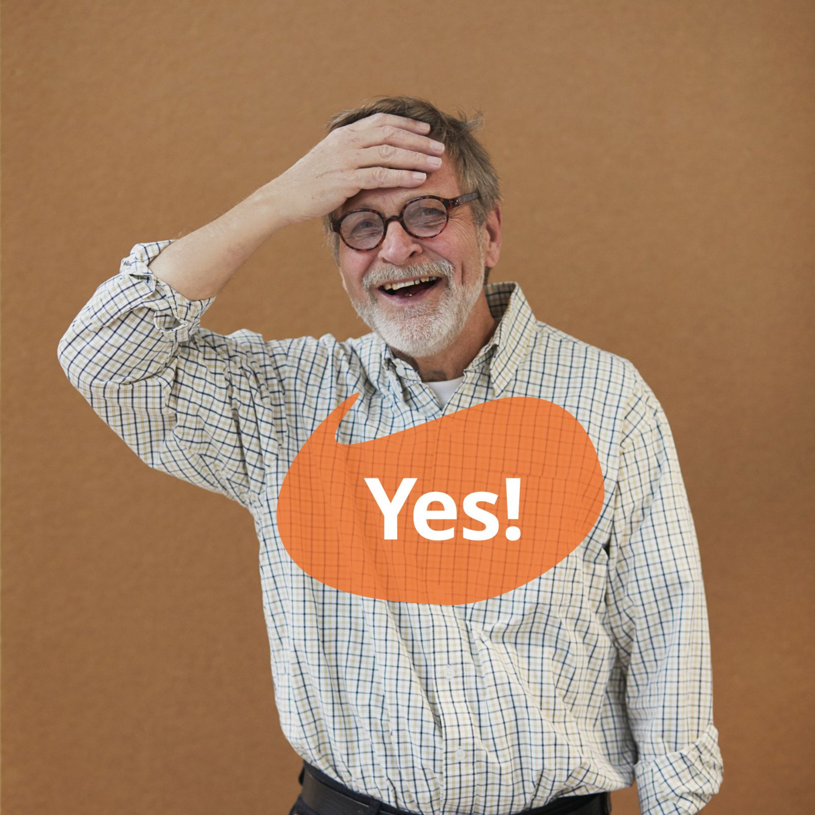 Grey-haired man in check shirt smiles and puts his hand to his forehead. A speech bubble contains the text 'Yes'.