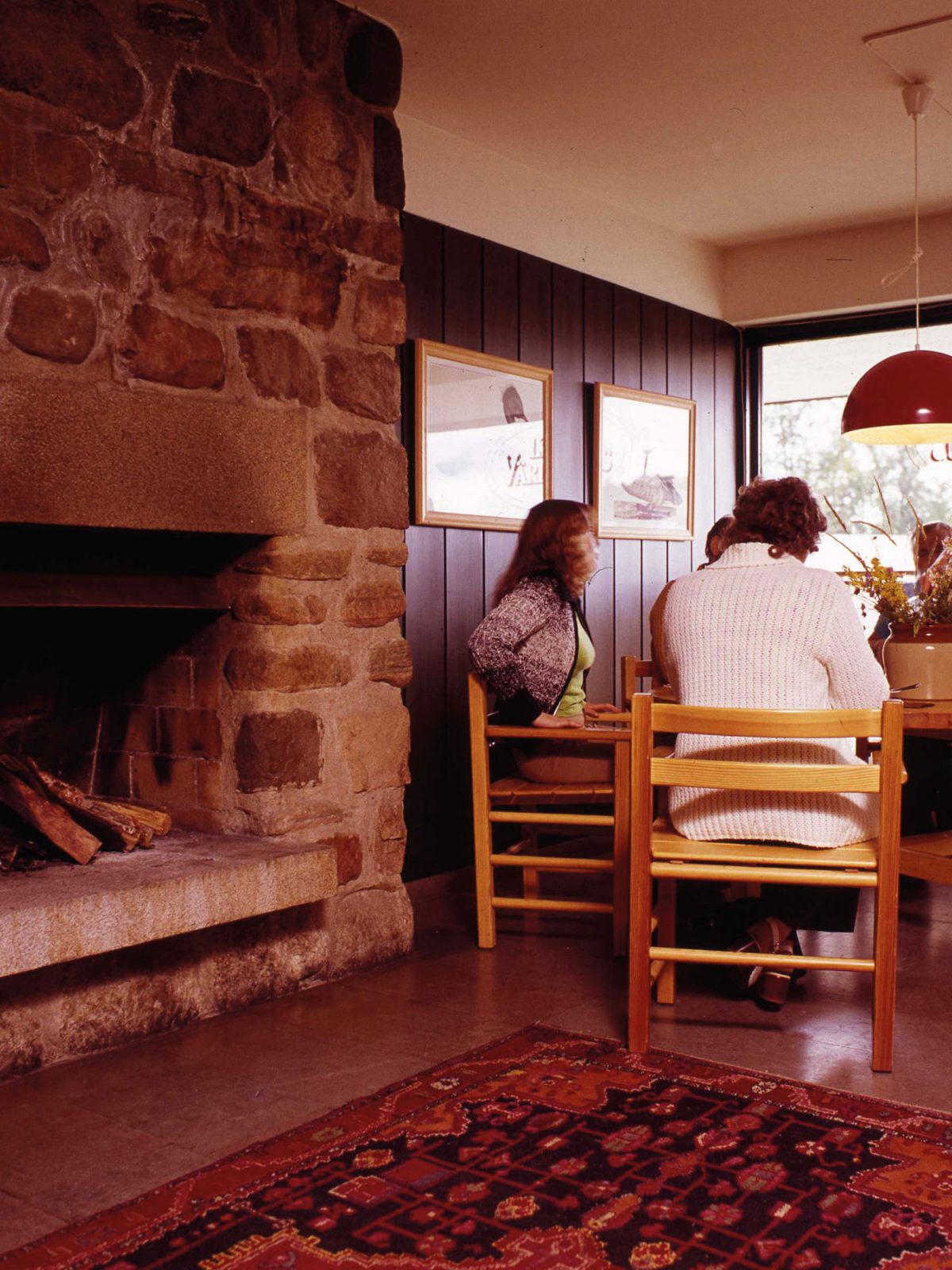 Brick fireplace in 1970s style restaurant, diners sitting at a table.