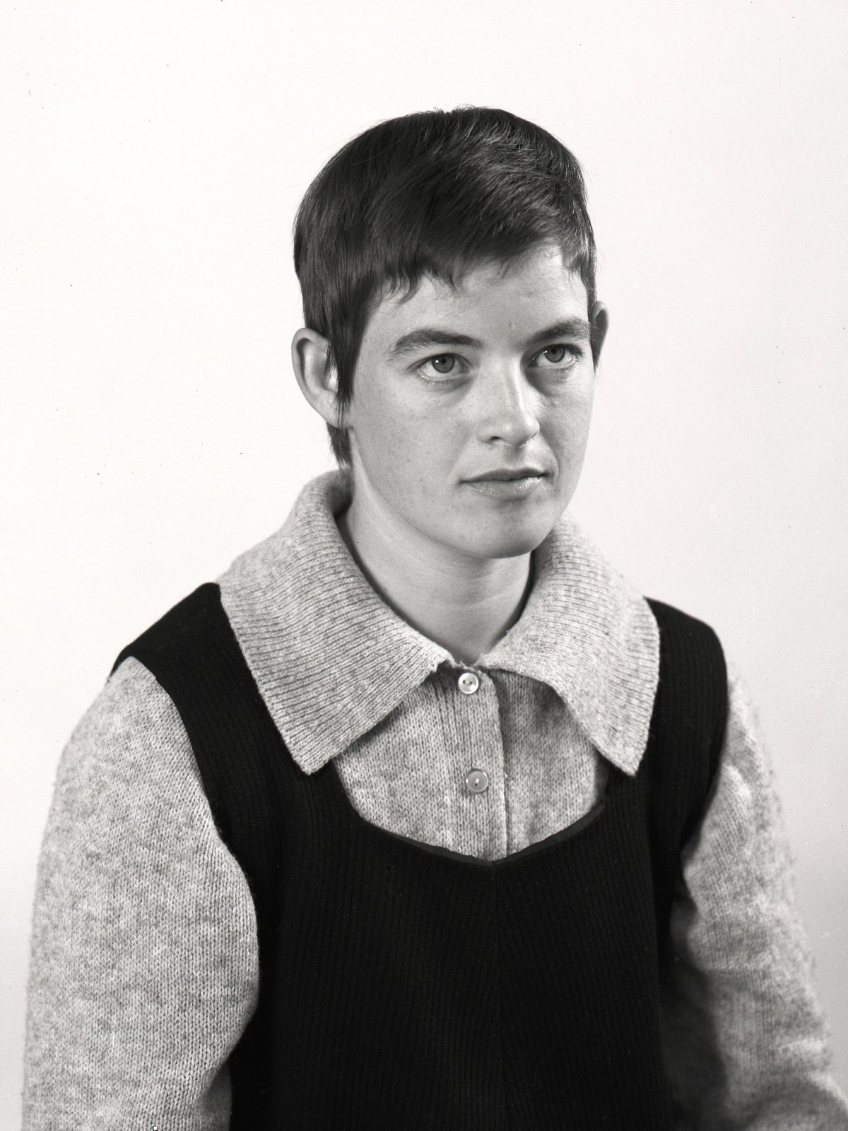Young woman with cropped hair, dressed in knitted sweater and dark vest, Bitten Højmark.