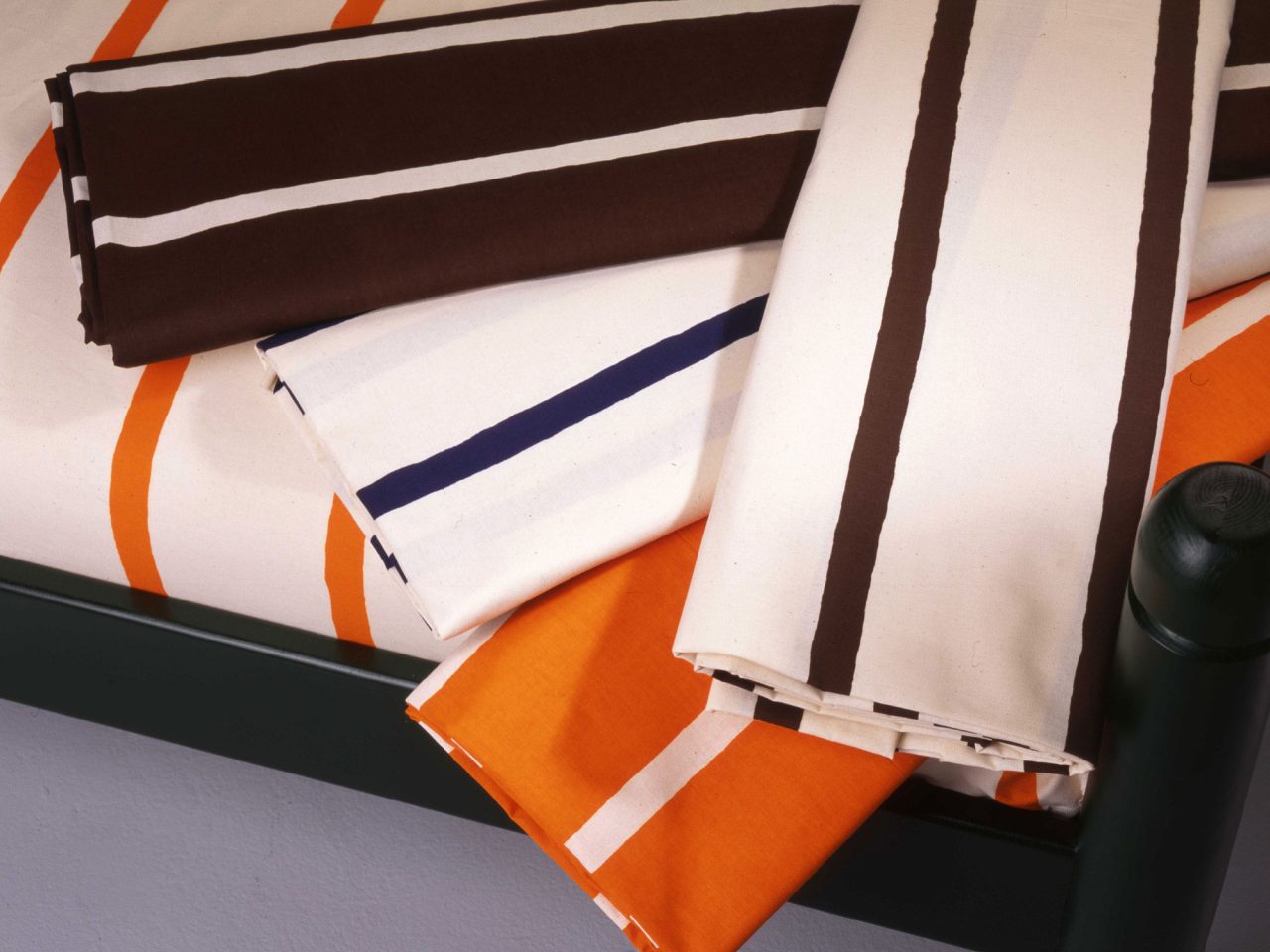 Rolls of striped fabrics in white and orange, black and white, and white and brown.