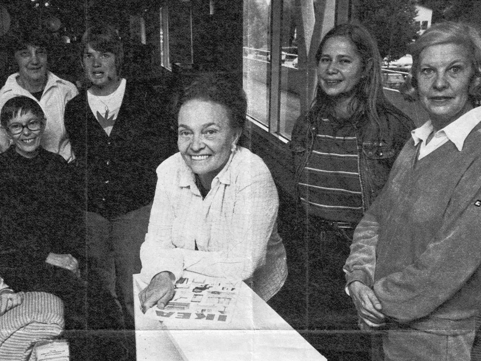 Gruppbild i tidning med sex kvinnor, ledigt klädda. En leende kvinna i vit skjorta håller i en IKEA katalog från 1980-talet.