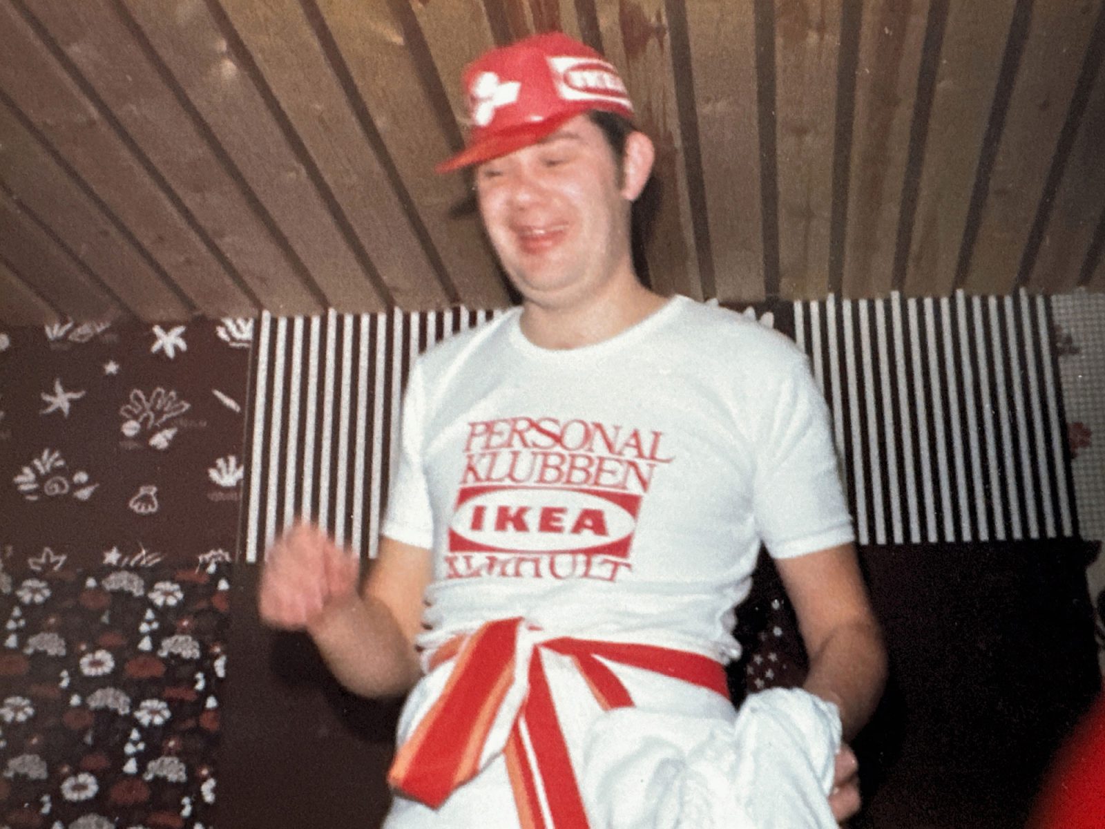 Dark-haired young man, Lars Göran Peterson, in a white IKEA T-shirt and red cap.