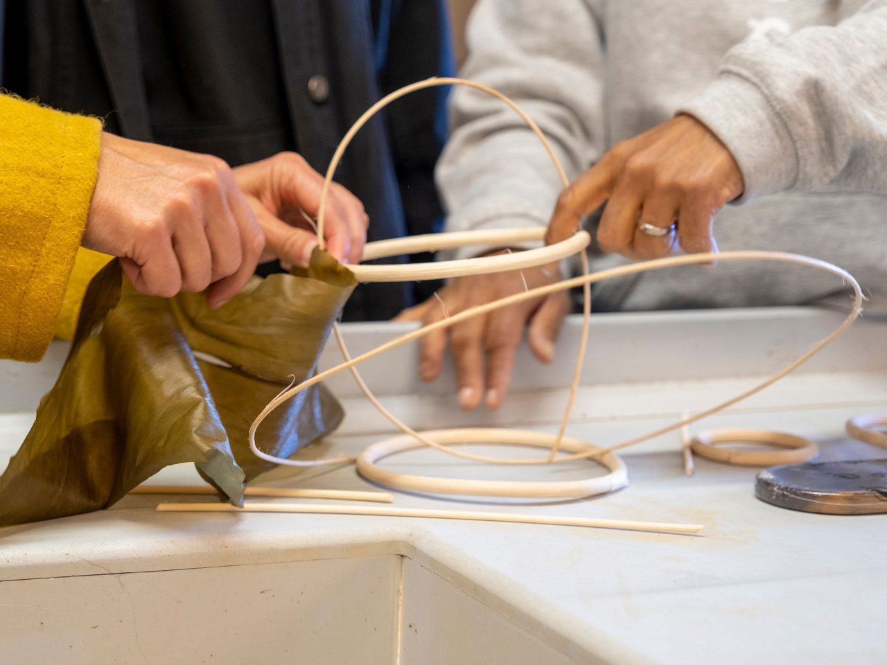 Close-up of two persons working with different materials during a workshop.
