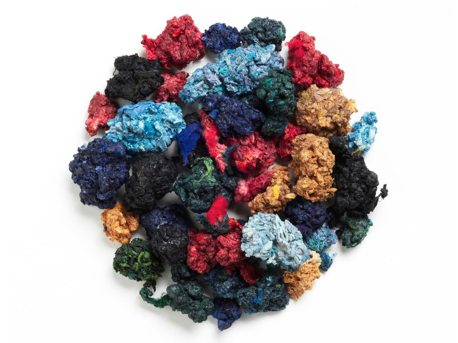 Round pile of textile scraps in different colours.