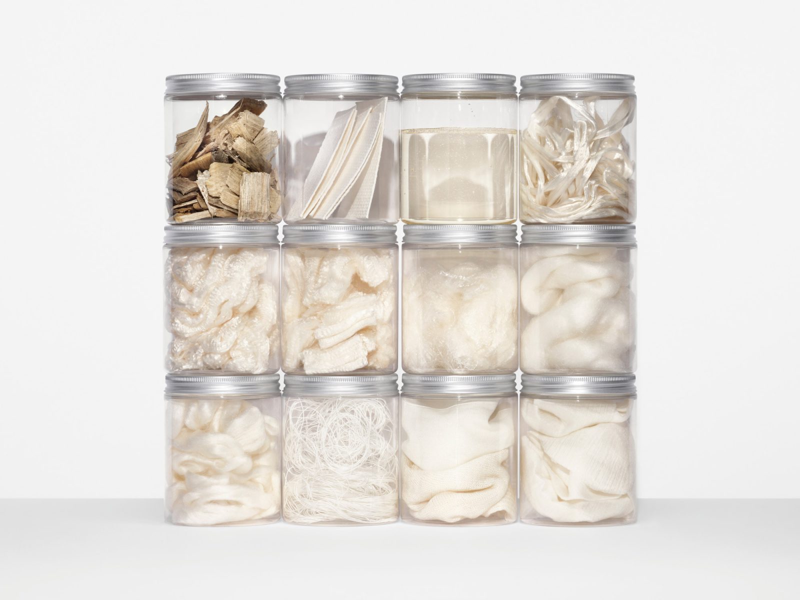 Glass jars containing light textile samples, stacked on each other.