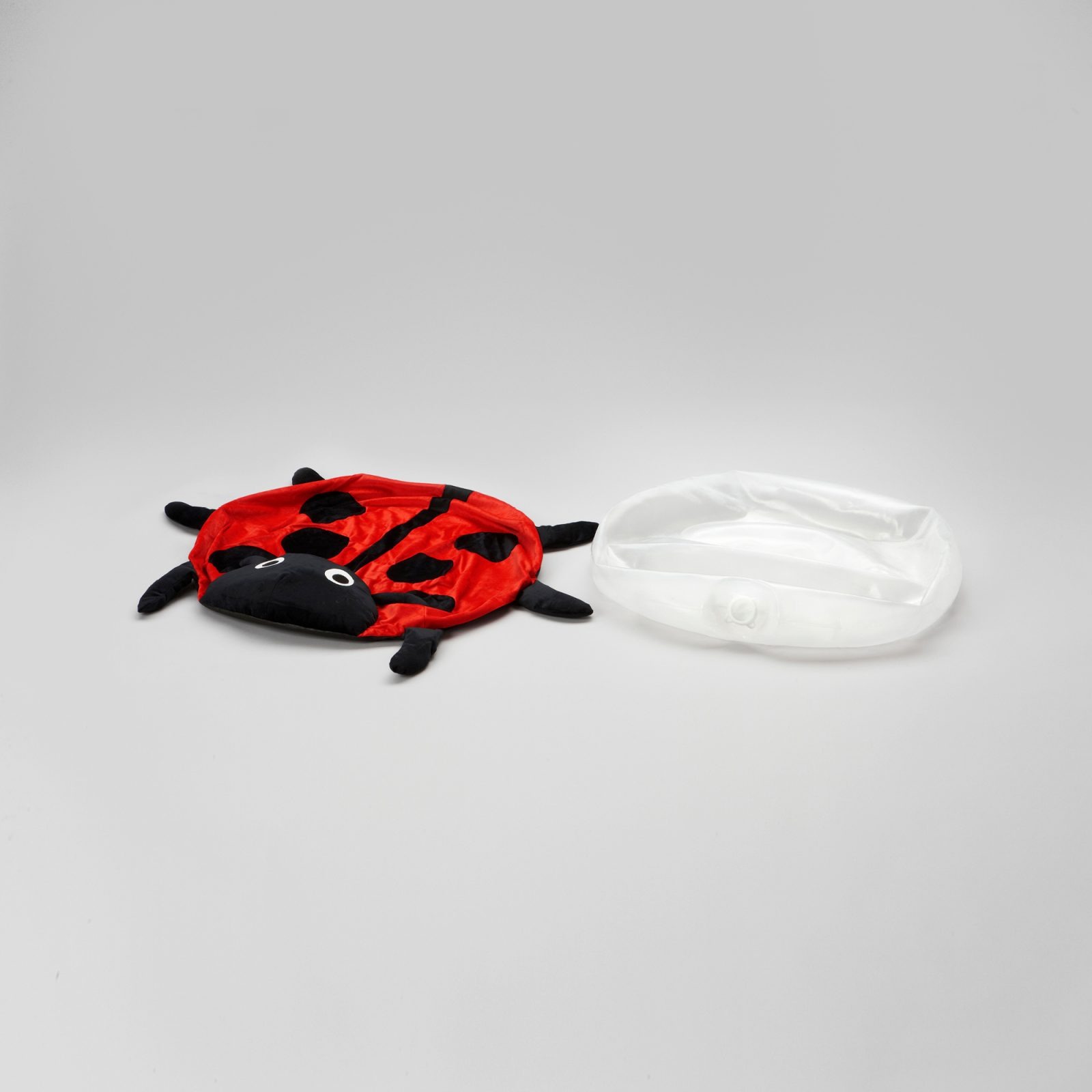 Pillow cover designed as a ladybird lies next to deflated plastic pillow.